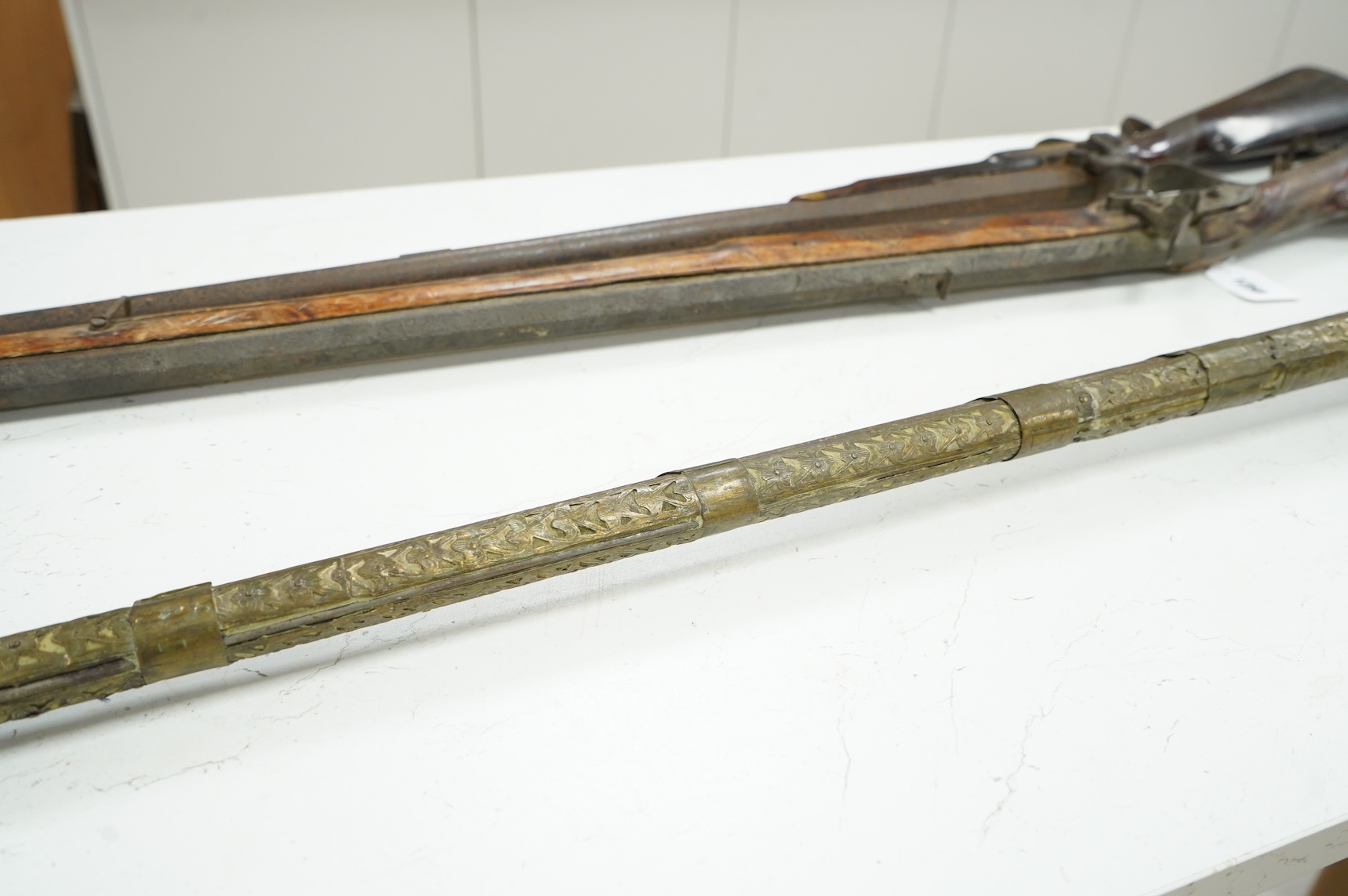 A Balkan miquelet flintlock gun with part octagonal Damascus twist barrel, silver inlaid at breach and muzzle, brass covered stock with shaped mother-of-pearl segments covering the butt, the side of stock inscribed ‘Piet